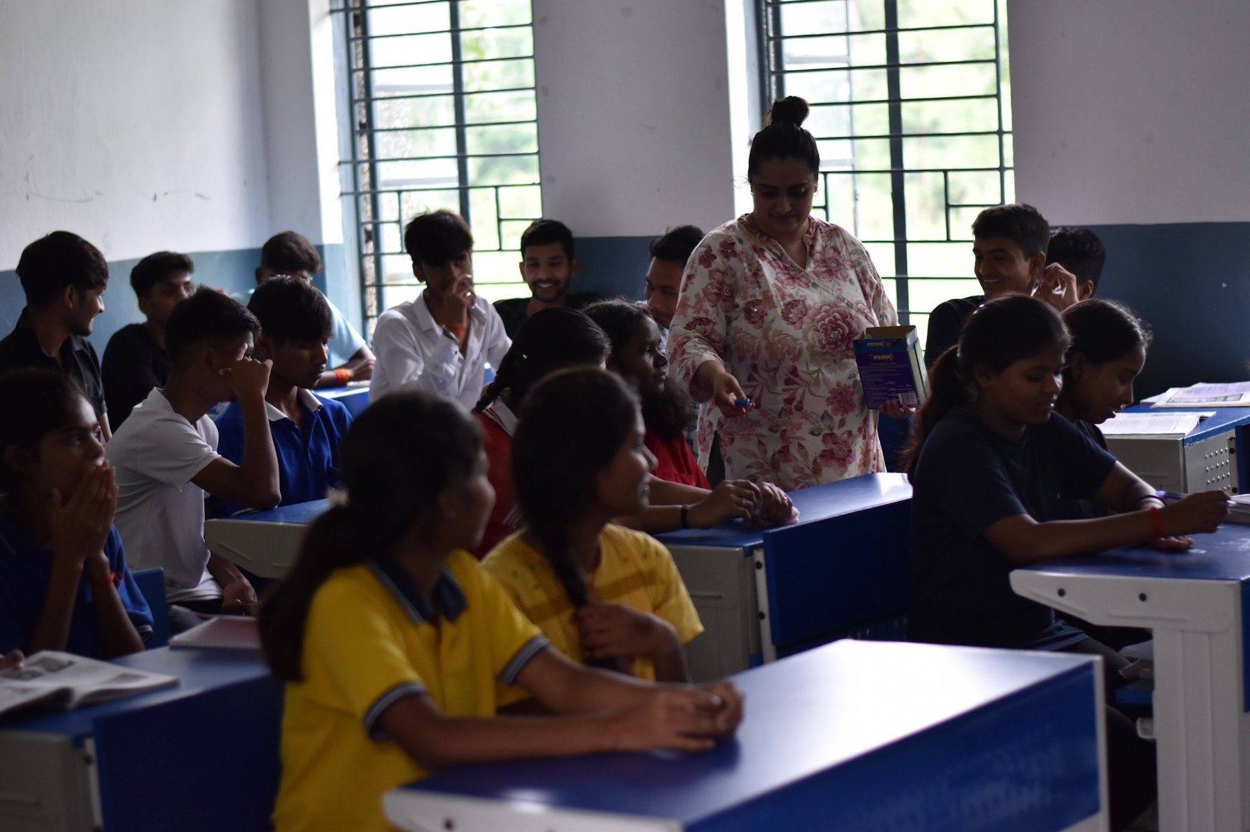 A facilitator moving through a classroom offering chocolates to students